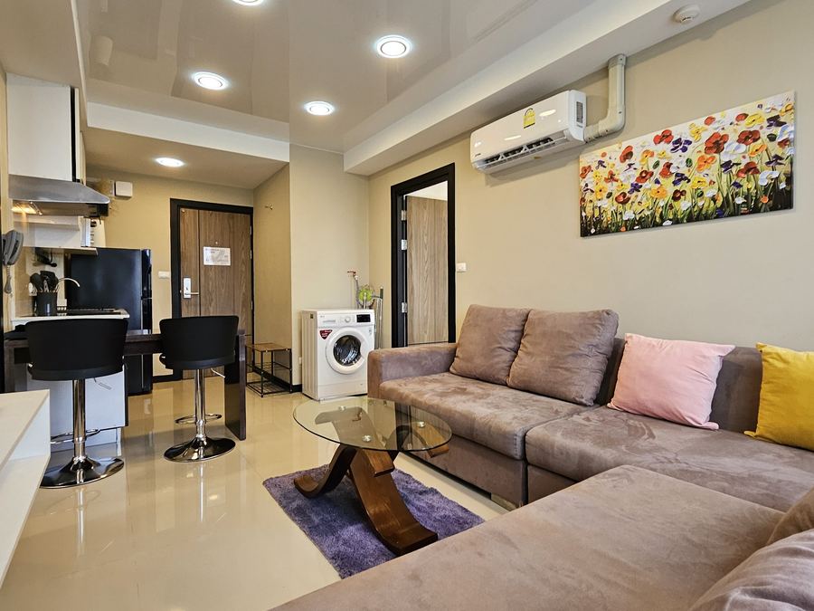 Mai Khao Beach Condotel: living room with corner sofa and kitchen